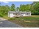 Back exterior of this home boasts a deck and a spacious yard with a gravel path leading to the driveway at 701 Oakwood St, Mebane, NC 27302