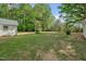 Expansive, grassy backyard showcasing lush greenery and mature trees, offering a serene outdoor space at 701 Oakwood St, Mebane, NC 27302