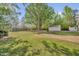Expansive backyard with mature trees, grass, and multiple outbuildings, providing ample space for outdoor activities at 701 Oakwood St, Mebane, NC 27302