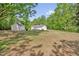 Charming white cottage-style home with a detached garage and a spacious front yard surrounded by mature trees at 701 Oakwood St, Mebane, NC 27302