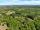 An aerial perspective captures homes surrounded by thick woodlands under a clear sky, highlighting the area's natural beauty at 7030 Shep Royster Rd, Oxford, NC 27565