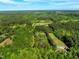 Scenic aerial shot exhibits a property encompassed by a dense forest, featuring clearings that show the home and surrounding greenery at 7030 Shep Royster Rd, Oxford, NC 27565