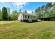 Features a well-kept lawn alongside wooded area, seamlessly integrating nature and living space at 7030 Shep Royster Rd, Oxford, NC 27565