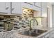 Kitchen sink featuring a stainless steel faucet, granite countertops, and modern tile backsplash at 7030 Shep Royster Rd, Oxford, NC 27565