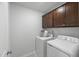 Well-lit laundry room with upper cabinets and modern, white washer and dryer appliances at 80 Spotted Bee Way, Youngsville, NC 27596