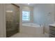 Bathroom featuring a corner tub beneath a window and tiled walk-in shower with neutral finishes at 800 Gathering Park Cir # 204, Cary, NC 27519