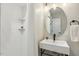 Bright bathroom featuring tiled shower, floating shelves, and modern vanity with a round mirror at 814 Ellynn Dr, Cary, NC 27511