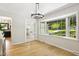 Bright dining room featuring hardwood floors, a modern chandelier, and a large bay window offering views of the landscaped front yard at 814 Ellynn Dr, Cary, NC 27511