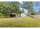 A spacious, grassy backyard including an outbuilding, partially surrounded by a wooden fence at 820 Southern St, Selma, NC 27576
