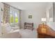 Cozy Bedroom featuring a crib, a white armchair, and a window with green trees outside at 8504 Boot Ct, Raleigh, NC 27615