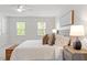 Sunlit bedroom with two windows, a ceiling fan, and comfortable bed with a woven storage trunk at 8504 Boot Ct, Raleigh, NC 27615