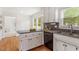Open concept kitchen with hardwood flooring, a black dishwasher, and an access to a sunlit room at 8504 Boot Ct, Raleigh, NC 27615