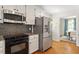 Kitchen featuring stainless steel appliances, granite countertops, and white cabinets with black backsplash at 8504 Boot Ct, Raleigh, NC 27615