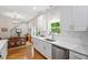 Bright kitchen with white cabinets, stainless steel dishwasher, and dining room view at 905 Carroll St, Durham, NC 27701