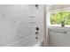 Bright bathroom shower with marble subway tiles, glass shelves and a window at 905 Carroll St, Durham, NC 27701