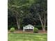 Serene garden view featuring a white bench nestled between trees and manicured shrubbery at 9301 Brookton Ct, Raleigh, NC 27615