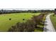 Lush aerial view of a green field dotted with hay bales, trees and gravel road at 1 Deer Run Trl, Hillsborough, NC 27278
