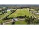 Scenic aerial view of green fields, tree lined roads, a pond and a house at 1 Deer Run Trl, Hillsborough, NC 27278