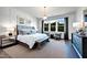 Bright main bedroom featuring a large window, pendant lighting, sitting area, and board and batten accent wall at 1 Deer Run Trl, Hillsborough, NC 27278