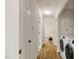 Hallway with hardwood floors, white walls, and laundry area at 101 Creekview Cir, Carrboro, NC 27510