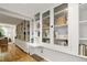 Living room with custom white built-in shelving and storage along with hardwood flooring throughout at 101 Creekview Cir, Carrboro, NC 27510