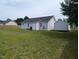 A backyard with grass, a shed, and the back of the house, with a fence visible in the background at 111 Shadow Bend Ln, Selma, NC 27576