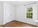 Clean bedroom with hardwood floors, a double closet, and large window overlooking lush greenery at 1121 Silky Dogwood Trl, Apex, NC 27502