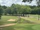 Scenic view of a lush golf course with sand traps and mature trees, offering a serene golfing experience at 118 Chanute Cir, Louisburg, NC 27549