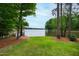Scenic backyard view with lush lawn and direct access to a serene lake, framed by mature trees at 118 Duncansby Ct, Cary, NC 27511