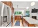 Open kitchen with stainless steel appliances, and white counters next to an open living area with a fireplace at 121 Ladybug Ln, Chapel Hill, NC 27516
