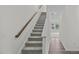 Carpeted staircase with a wood banister and white walls leads to the upper level at 1215 Pond Overlook Drive, Nashville, NC 27856