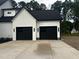 View of a two-car garage featuring modern black doors and sleek white exterior at 123-125 Ottawa Dr., Louisburg, NC 27549