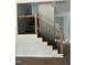 Modern staircase with a wooden banister and black metal spindles with natural light at 123-125 Ottawa Dr., Louisburg, NC 27549