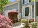 Inviting front entrance with a classic black door, white trim, and lush landscaping, set with a security system sign at 1911 Housatonic Ct, Apex, NC 27523
