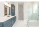 Modern bathroom with a glass-enclosed shower, white tile floors and blue vanity at 2 Deer Run Trl, Hillsborough, NC 27278