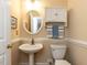 Powder room with pedestal sink, decorative mirror, and storage cabinet at 204 Highlands Lake Dr. Dr, Cary, NC 27518