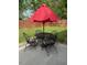 Cozy patio setup with a black metal table and chairs, topped with a vibrant red umbrella at 212 Orange St, Oxford, NC 27565