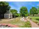 Spacious backyard featuring a cozy fire pit with white chairs, colorful flower beds, and a quaint yellow garden shed at 220 Lakecroft Pl, Fuquay Varina, NC 27526