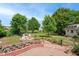 Beautifully landscaped backyard featuring a fire pit with white Adirondack chairs, brickwork, lush greenery, and a garden shed at 220 Lakecroft Pl, Fuquay Varina, NC 27526
