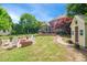 Expansive backyard featuring a brick fire pit with Adirondack chairs, manicured lawn, and a charming yellow garden shed at 220 Lakecroft Pl, Fuquay Varina, NC 27526