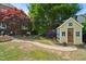Charming backyard featuring a quaint yellow shed, brick pathway, and lush greenery creating a serene outdoor oasis at 220 Lakecroft Pl, Fuquay Varina, NC 27526