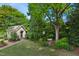 A charming backyard featuring a garden shed, bird bath, lush greenery, and stone pathway, enhancing its serene ambiance at 220 Lakecroft Pl, Fuquay Varina, NC 27526