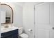 A well-lit powder room offers a vanity with modern fixtures, a toilet, and a white door, exuding a clean and functional style at 220 Lakecroft Pl, Fuquay Varina, NC 27526