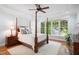 Primary bedroom showcasing a four-poster bed, tray ceilings, wood flooring, and bright windows at 220 Lakecroft Pl, Fuquay Varina, NC 27526