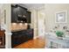 Butler Pantry features dark cabinetry, tile backsplash, wooden floors, and trimmed doorway in neutral colored home at 220 Lakecroft Pl, Fuquay Varina, NC 27526