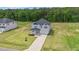 Expansive aerial view of a two-story home with a long driveway, surrounded by green lawns and woods at 234 Robert Howe Dr, Fuquay Varina, NC 27526