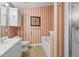 Bathroom with white vanity, beige countertops, shower-tub combination and striped red wallpaper at 2424 Cambridge Rd, Burlington, NC 27215