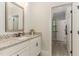A bright bathroom features granite countertops, white cabinets, modern fixtures, and an adjacent hallway, providing a functional space at 251 Gentry Dr, Pittsboro, NC 27312
