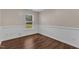 This bedroom features wood-look floors, wainscoting, and a window for natural light at 3608 Deering Dr, Raleigh, NC 27616