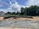New home foundation with block walls and a backyard entrance against a background of trees and cloudy skies at 37 Shoreline Dr, Lillington, NC 27546